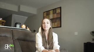 A woman shares a couch with her stepson in a taboo roleplay scene