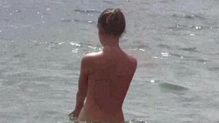 A group of nudists enjoy a day at the beach completely naked