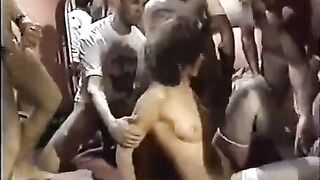 A young whore in stockings is having sex with many guys in a circle
