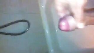 The kid caresses his dick with his hand in the shower