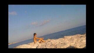 A young girl sunbathes naked on the beach to get a tan