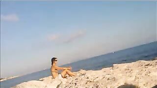 A young girl sunbathes naked on the beach to get a tan