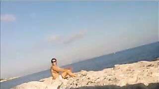 A young girl sunbathes naked on the beach to get a tan
