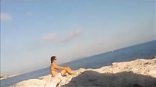 A young girl sunbathes naked on the beach to get a tan